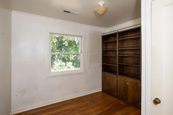 a view of an empty room with a window and wooden floor