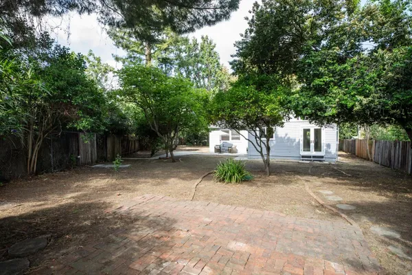 a backyard of a house with potted plants and trees