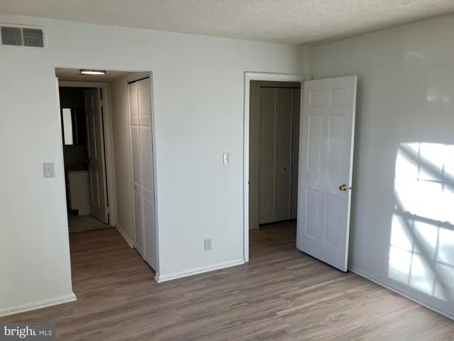 a view of a hallway with wooden floor and a bathroom