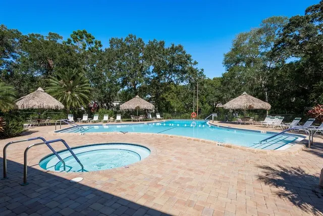 a view of a tennis ground with large trees and couches