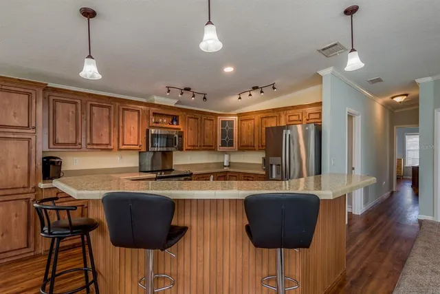 a kitchen with stainless steel appliances wooden floor and a refrigerator