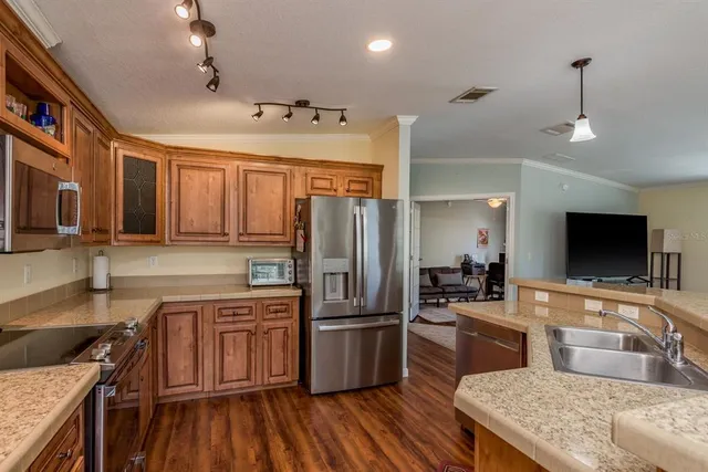 a large kitchen with stainless steel appliances granite countertop a stove top oven a sink dishwasher a dining table and chairs with wooden floor