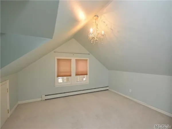 an empty room with a chandelier fan and windows
