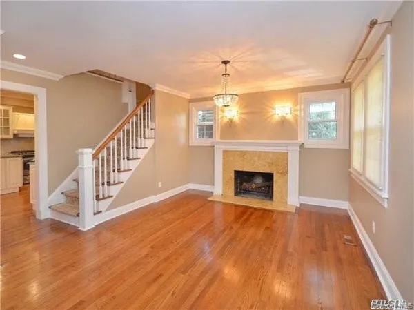 a view of an empty room with wooden floor fireplace and a window