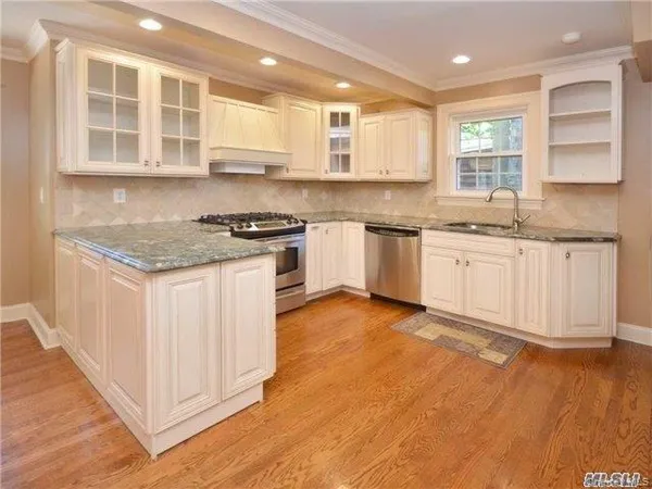 a kitchen with granite countertop a stove top oven a sink and cabinets