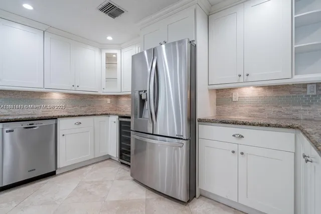 a kitchen with granite countertop white cabinets and refrigerator
