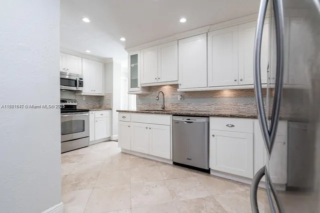 a kitchen with granite countertop white cabinets and stainless steel appliances