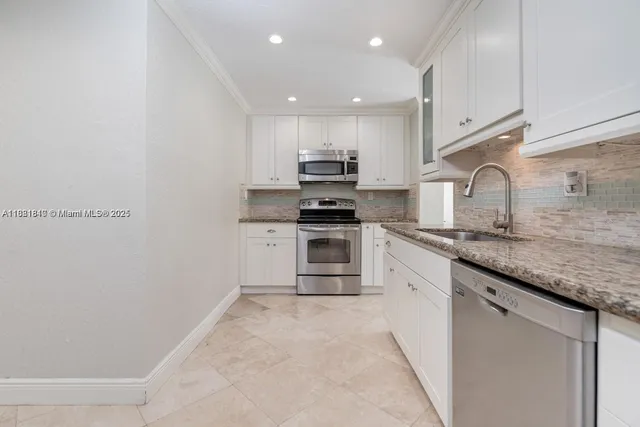 a large kitchen with granite countertop a stove top oven a sink a counter space and cabinets