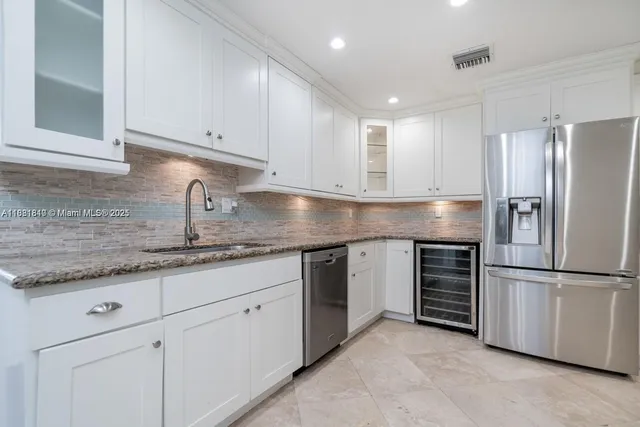 a kitchen with granite countertop a sink stainless steel appliances and cabinets
