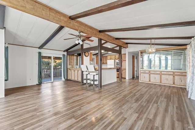 a view of an empty room with wooden floor and windows