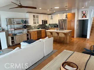 a large kitchen with stainless steel appliances kitchen island granite countertop a refrigerator a stove a sink a dining table and chairs with wooden floor