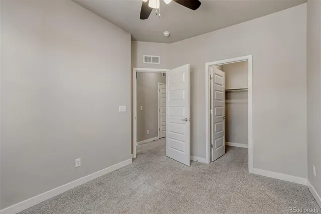 an empty room with closet and a chandelier fan