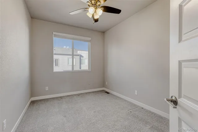 an empty room with a window and a fan
