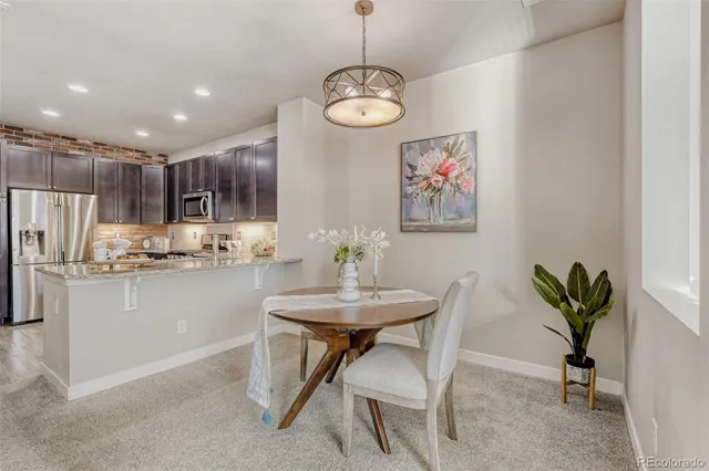 a dining room with kitchen island stainless steel appliances furniture a chandelier and a view of kitchen