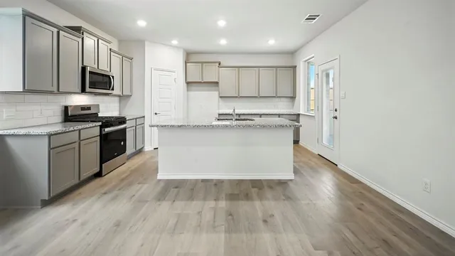 a large kitchen with stainless steel appliances granite countertop a stove top oven a sink dishwasher and a microwave oven on granite countertops