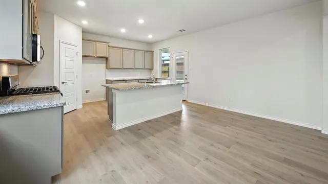 a kitchen with granite countertop a stove and a wooden floors