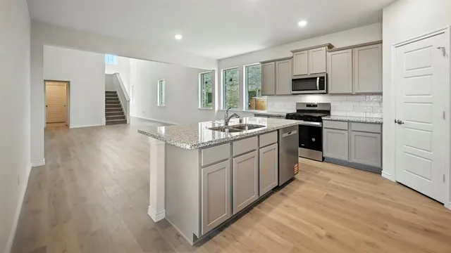 a kitchen with stainless steel appliances granite countertop a sink stove refrigerator and white cabinets with wooden floor
