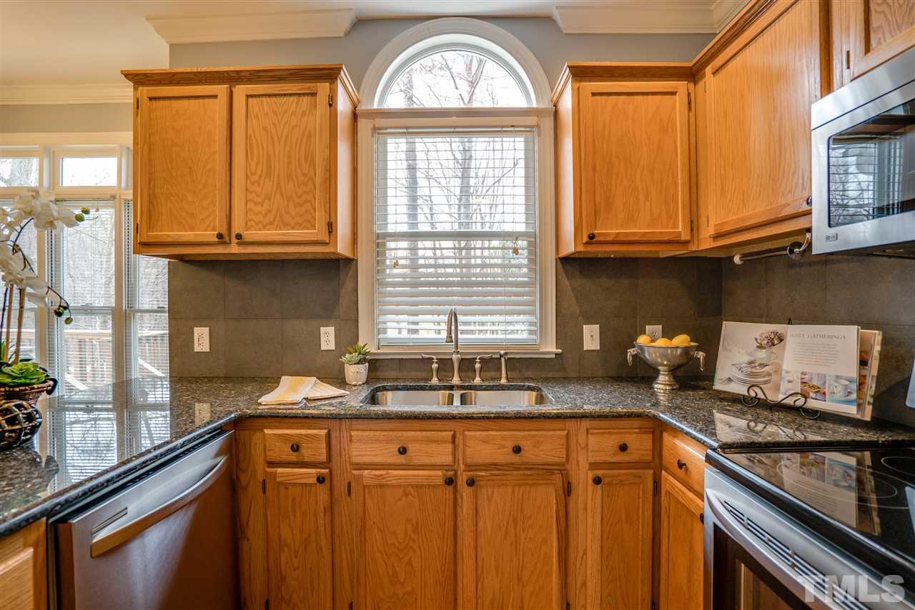 9905 Rimwood Court Raleigh, NC 27613 - Photo 11 of 24 a kitchen with stainless steel appliances granite countertop a sink a stove cabinets counter space and a window