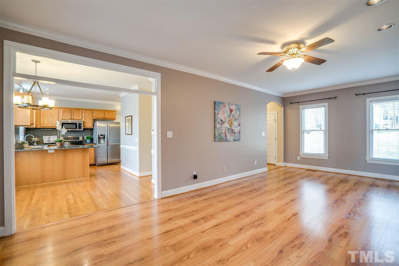 9905 Rimwood Court Raleigh, NC 27613 - Photo 6 of 24 a view of an empty room and kitchen with wooden floor and a ceiling fan