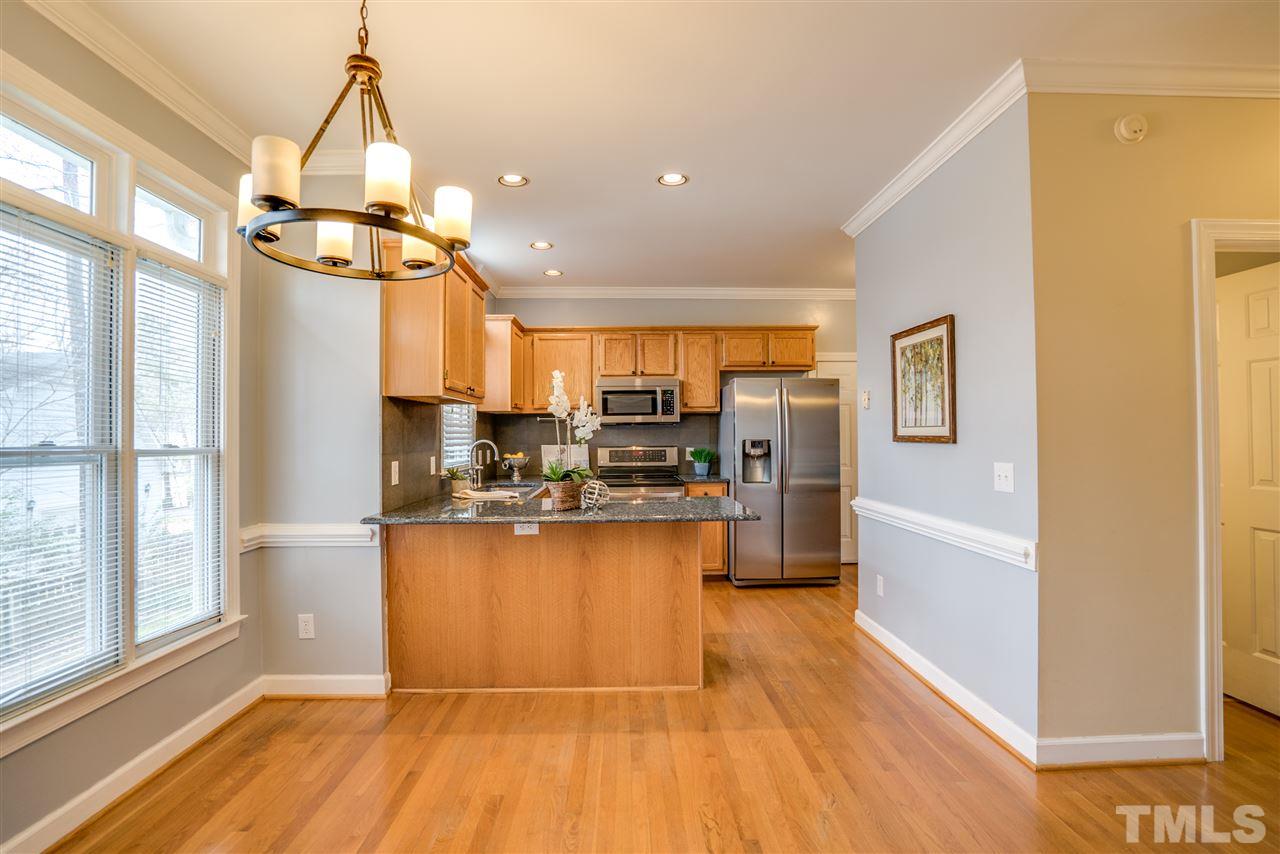 9905 Rimwood Court Raleigh, NC 27613 - Photo 7 of 24 a kitchen with stainless steel appliances granite countertop a refrigerator a sink dishwasher a stove and a dining table with wooden floor