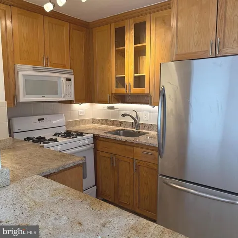 a kitchen with stainless steel appliances granite countertop a refrigerator stove top oven and sink