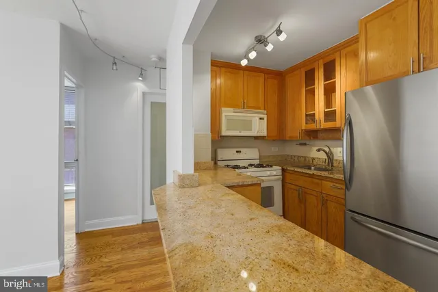 a kitchen with stainless steel appliances granite countertop a refrigerator a stove and a sink with granite countertops