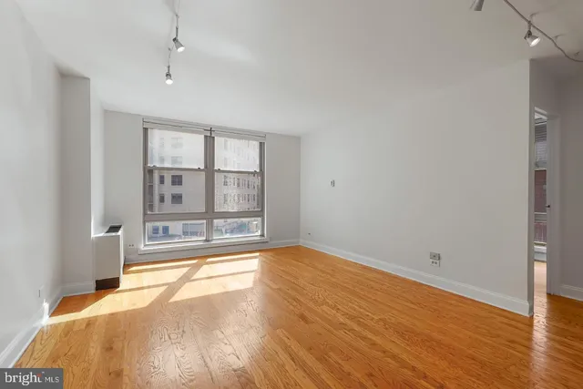 a view of empty room with wooden floor and fan