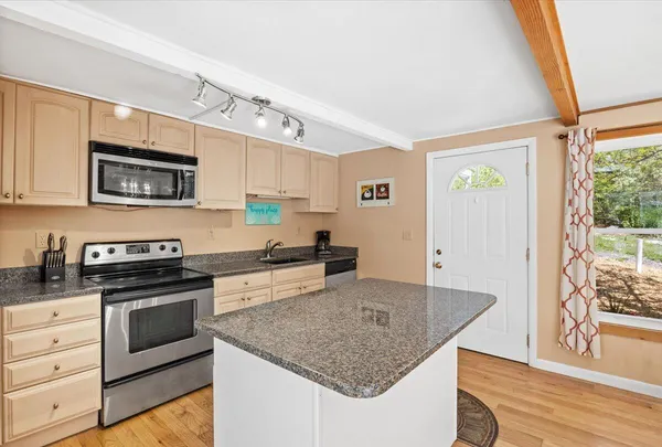 a kitchen with stainless steel appliances granite countertop a stove a sink and a microwave