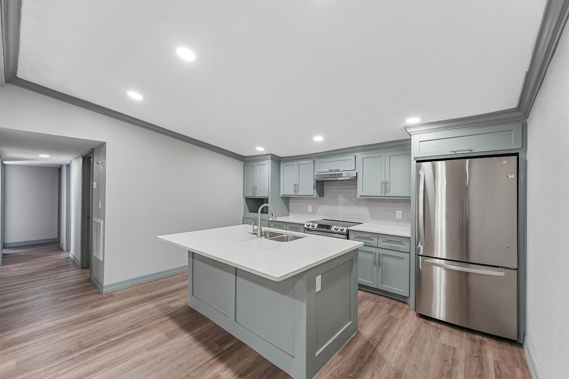 a kitchen with a refrigerator a sink and wooden floor
