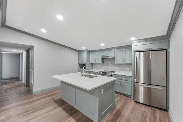 a kitchen with a refrigerator a sink and wooden floor