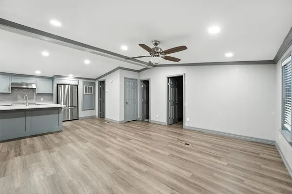 a view of an empty room with kitchen and a window