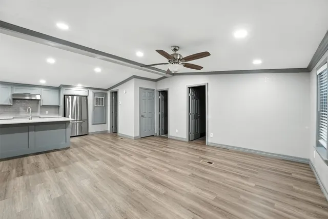 a view of an empty room with kitchen and a window