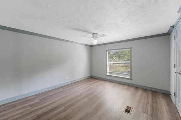 an empty room with wooden floor and windows