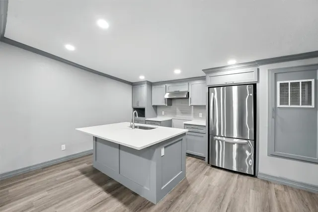 a kitchen with a refrigerator a sink and wooden floor
