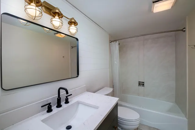 a bathroom with a sink a toilet and shower