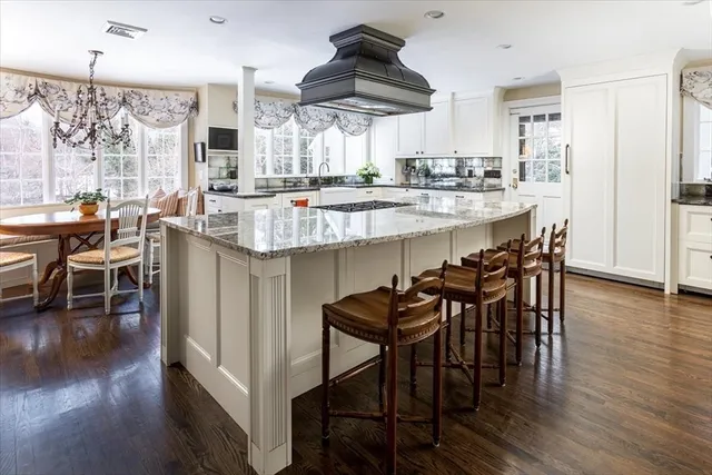 a kitchen with stainless steel appliances granite countertop a table and chairs in it