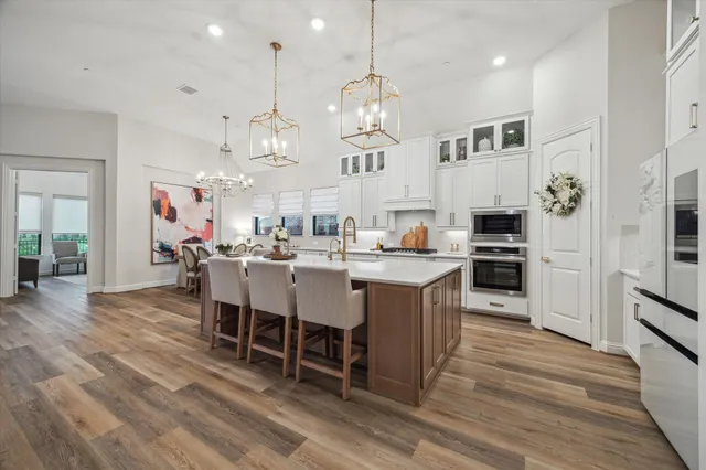 a kitchen with stainless steel appliances kitchen island granite countertop a table chairs and a refrigerator