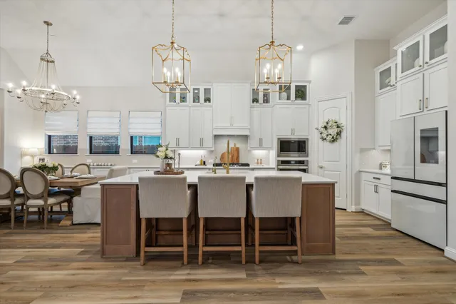 a dining room with stainless steel appliances kitchen island granite countertop a dining table chairs and granite counter tops