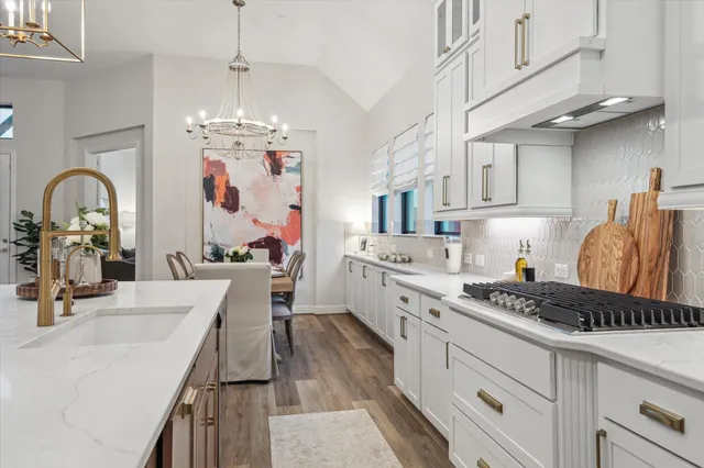 a kitchen with granite countertop a stove a sink dishwasher and white cabinets with wooden floor