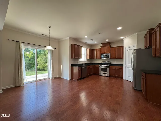 a kitchen with stainless steel appliances kitchen island granite countertop a refrigerator a stove a sink and a large window