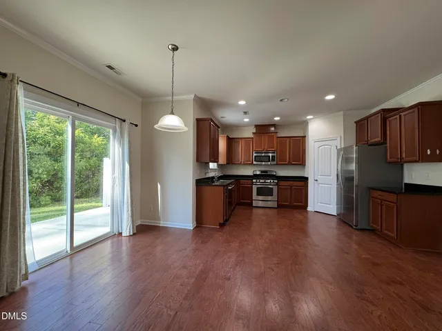 a kitchen with stainless steel appliances granite countertop a refrigerator a sink a stove and a wooden floors