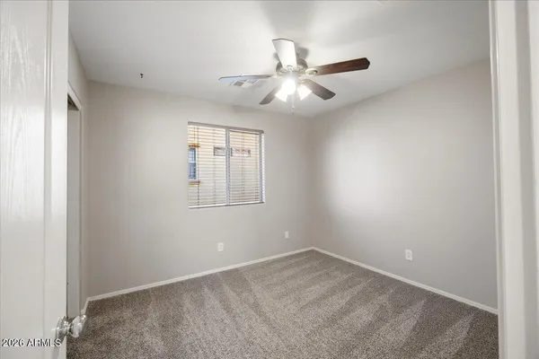 an empty room with a window and ceiling fan