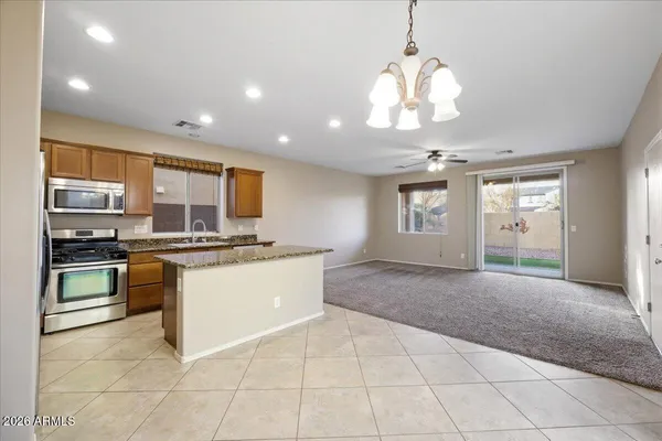 a large kitchen with kitchen island granite countertop a stove a sink a counter space and cabinets