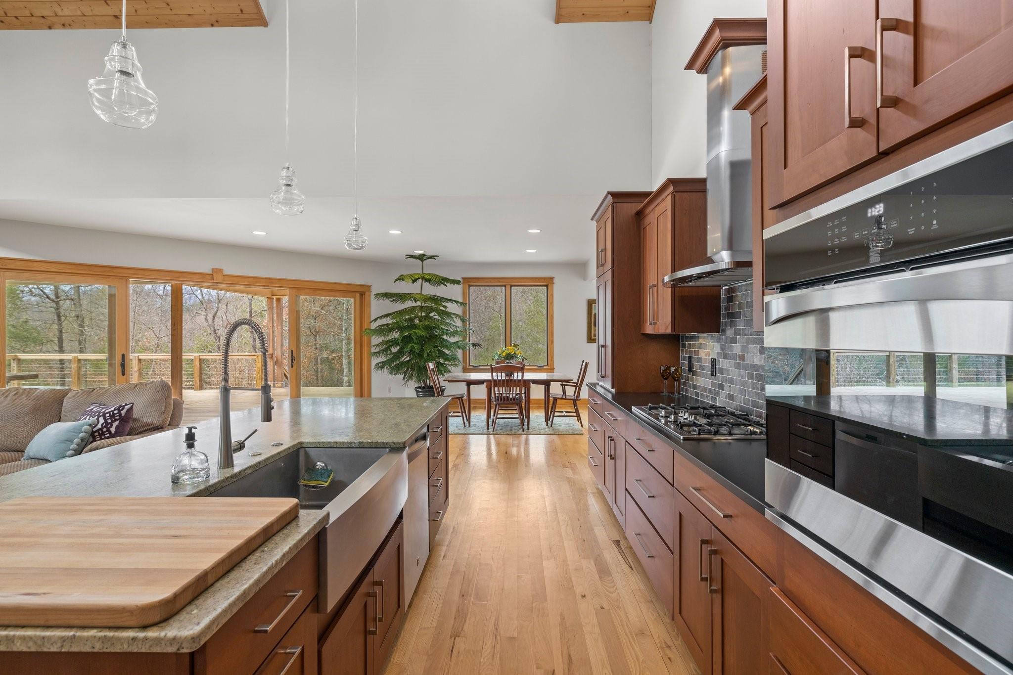 41 Rowan Hl Road Leicester, NC 28748 - Photo 17 of 48 a kitchen with stainless steel appliances kitchen island granite countertop a stove top oven a sink a dining table and chairs with wooden floor