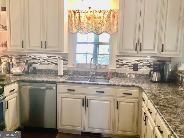 a kitchen with granite countertop white cabinets and a window