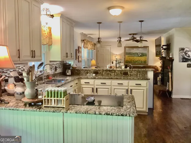 a kitchen with kitchen island granite countertop a sink cabinets and wooden floor