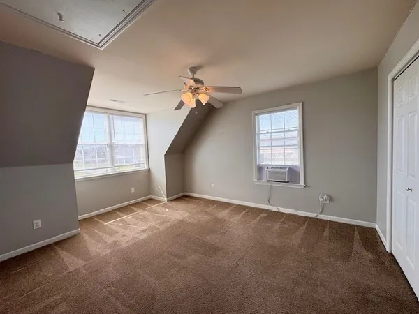 an empty room with windows and fan