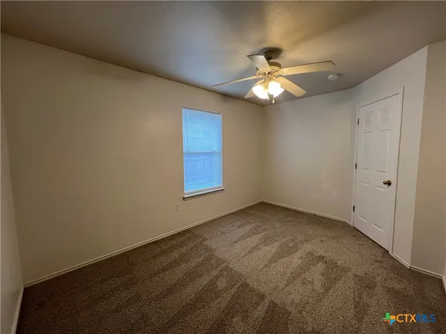 a view of an empty room and chandelier fan and window
