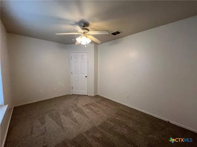 an empty room with a window and a fan