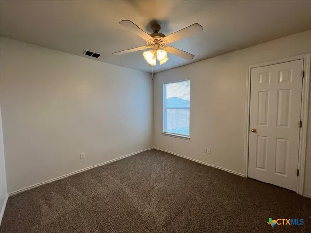 an empty room with window and ceiling fan